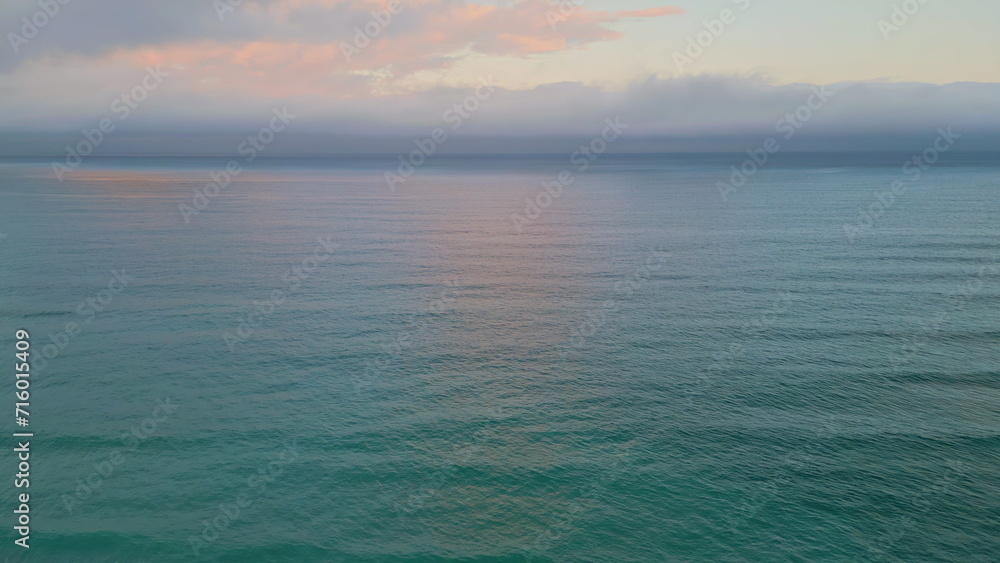 Rippling ocean surface reflecting beautiful sunset. Aerial view marine sunrise