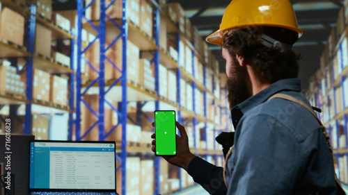 Photography Delivery station associate works with greenscreen display in warehouse depot, checking stock logistics for new parcel shipment