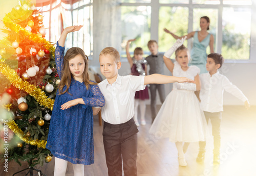 Christmas ball - beautifully dressed children dance the Viennese waltz near the New Year tree