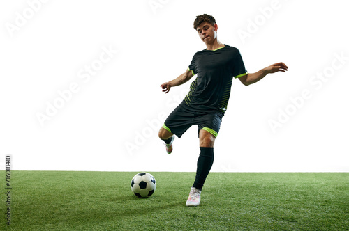 Young man, football player in motion during game, hitting ball isolated over white background with grass flooring. Concept of sport, game, competition, championship, active lifestyle © master1305