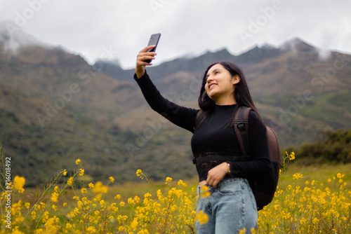 Una chica turista con mochila y celular tomandose un selfie en el paraíso floral, Encanto primaveral, tecnología y flores amarillas en armonía.