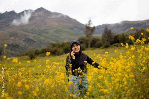 Una foto de una chica turista con gorra y mochila usando un smartphone durante la publicidad ,Encanto primaveral, tecnología y flores amarillas en armonía.