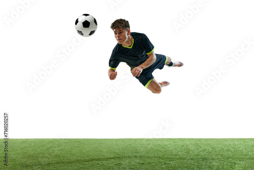 Dynamic image of young man, football player in motion, hitting ball with head isolated over white background with grass flooring. Concept of sport, game, competition, championship, active lifestyle © master1305