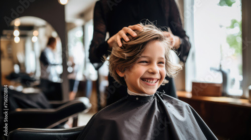 happy smiling child sitting in a chair at the hairdresser, haircut, hairstyle, style, girl, boy, kid, toddler, fashion, beauty salon, barbershop, hair, portrait, face, emotional © Julia Zarubina