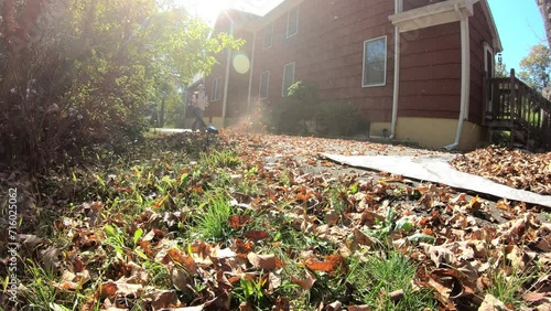 time lapse woman blowing and raking the leaves in the driveway in the fall photo