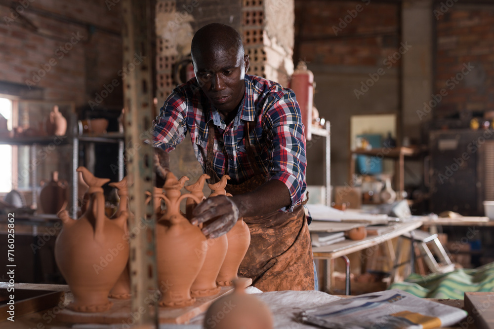Skilled craftsman working in pottery, checking quality of ceramic objects