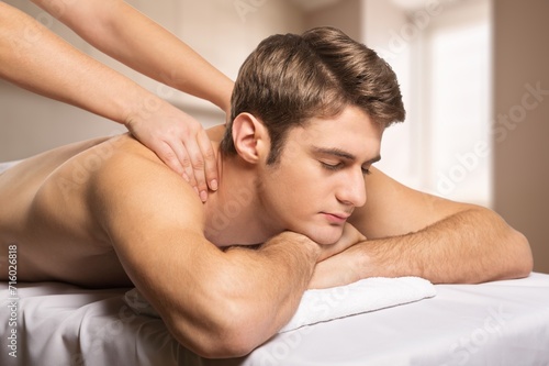 Handsome man has back massage in salon, relaxing after work.