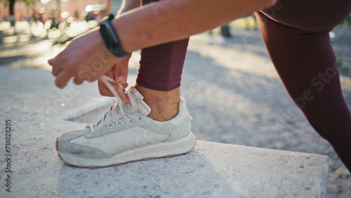 Fototapeta Naklejka Na Ścianę i Meble -  Woman hands tying laces on sneakers outdoor closeup. Runner lacing up footwear