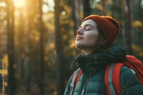 Young woman with eyes closed breathing fresh air while camping in woods photo