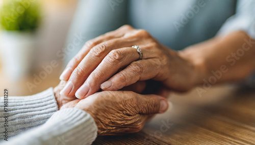 young woman and a senior lady, as they share a tender hand-holding moment, symbolizing intergenerational love and care photo