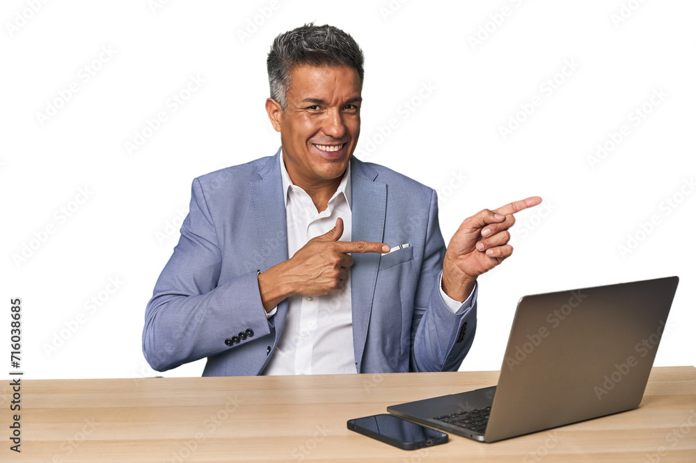 Elegant businessman at desk with laptop excited pointing with forefingers away. Elegant businessman at desk with laptop excited pointing with forefingers away.
