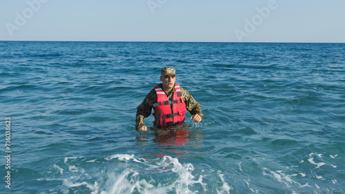 Soldier with life jacket comes out of the sea