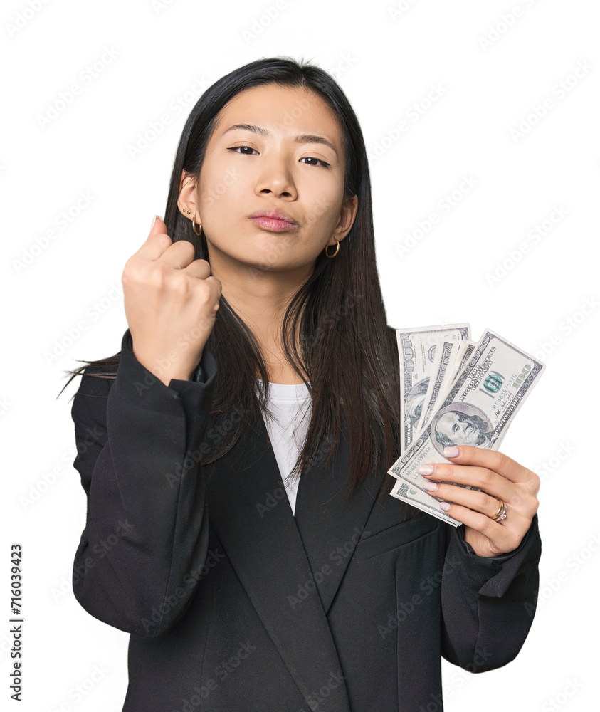 Young Chinese woman with dollars in suit showing fist to camera, aggressive facial expression. Young Chinese woman with dollars in suit showing fist to camera, aggressive facial expression.