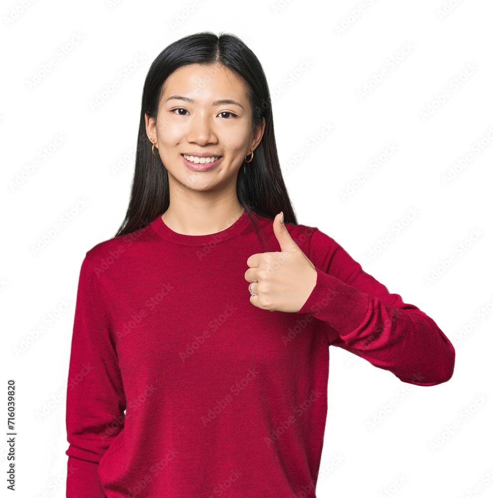 Young Chinese woman in studio setting smiling and raising thumb up Young Chinese woman in studio setting smiling and raising thumb up