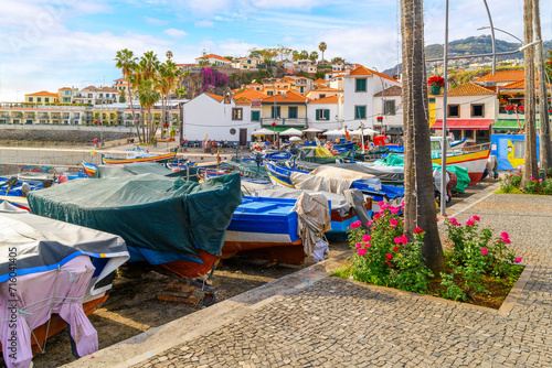 Colorful small fishing boats of blue, yellow and red line the small marina harbor at the small fishing village of Câmara de Lobos, Madeira, Portugal, in the Canary Islands. photo