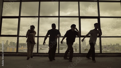 Silhouette shot of skilled choreographer group dancing together with sky scrapper, cityscape background. Young hipster team dancing performance. Sepia filter. Shadow. Outdoor sport 2024. Endeavor.