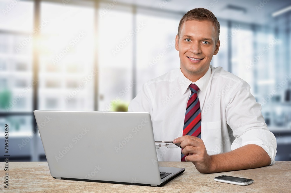Happy business man sitting in office with laptop. Happy business man sitting in office with laptop.