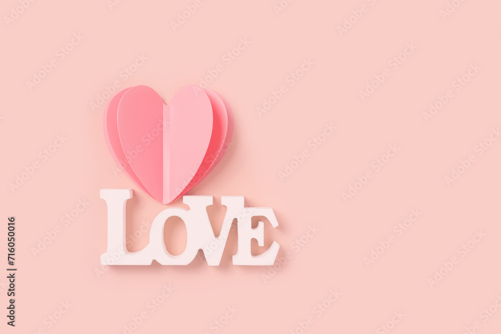 Heart and word love, St. Valentine Day, love or wedding day concept. Cut pink paper heart and white wooden text love as symbol romantic relationships, pink color background, minimal flatlay