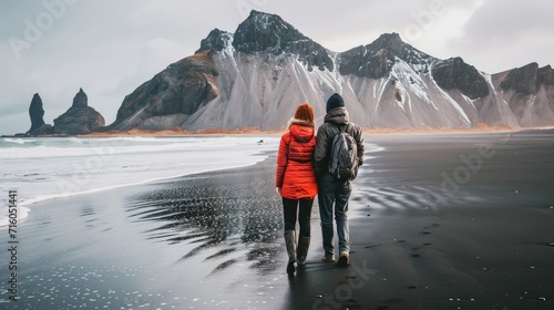 A traveling couple enjoys incredible views of the mountains from a black beach in Iceland generative ai