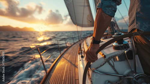 A male yachtsman steers a yacht in the sea.