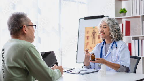 Mature asian doctor explaining prescription medication to an attentive senior male patient during a consultation..