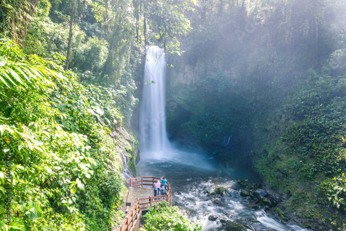 Couple looking at La Paz waterfall in the green rainforest of Costa Rica photo