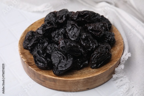 Sweet dried prunes on white tiled table, closeup