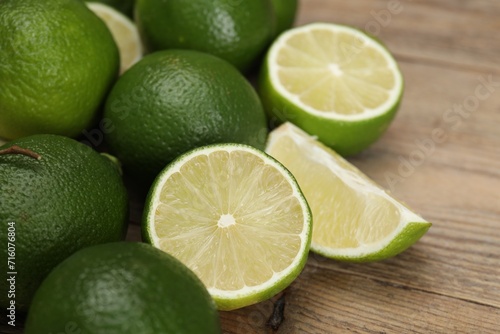 Fresh whole and cut limes on wooden table, closeup