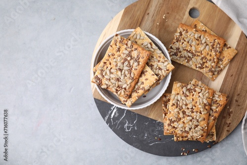 Cereal crackers with flax, sunflower and sesame seeds on grey table, top view. Space for text