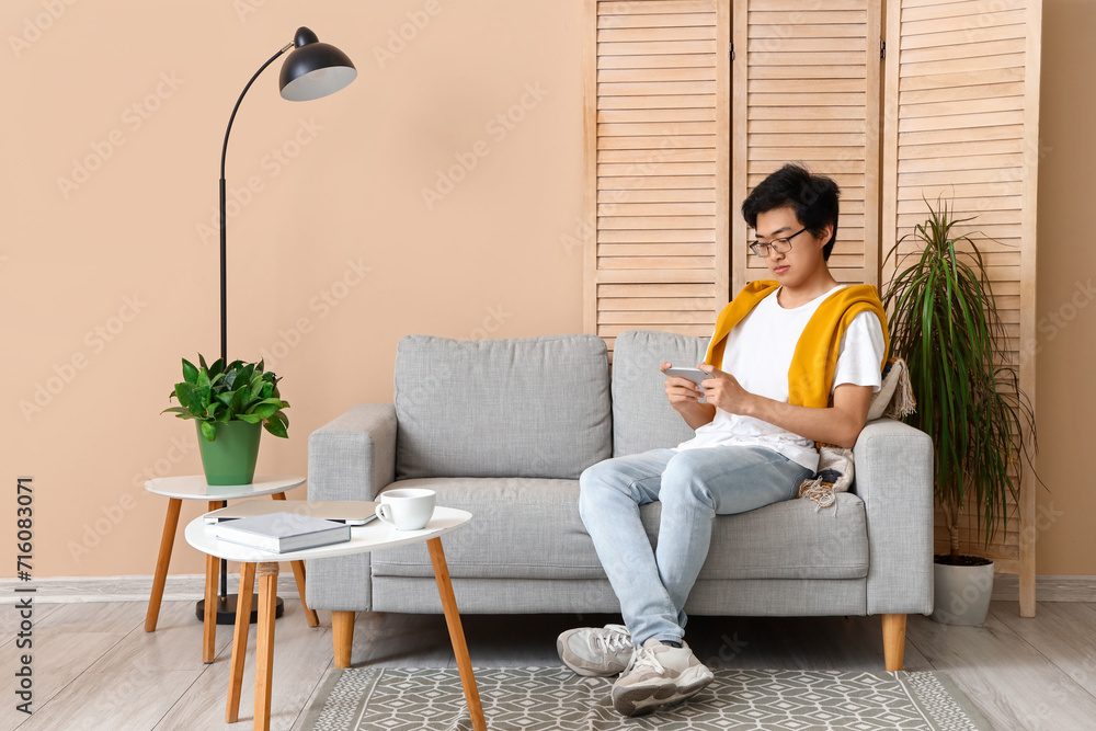 Young Asian man using mobile phone on his day off at home Young Asian man using mobile phone on his day off at home