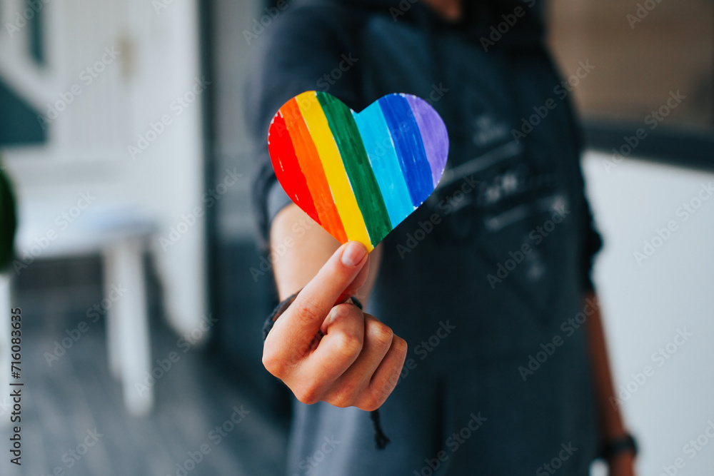 Photograph of man's hands holding a hand drawn LGBTQ+ heart. Concept of people and lifestyles. Photograph of man's hands holding a hand drawn LGBTQ+ heart. Concept of people and lifestyles.