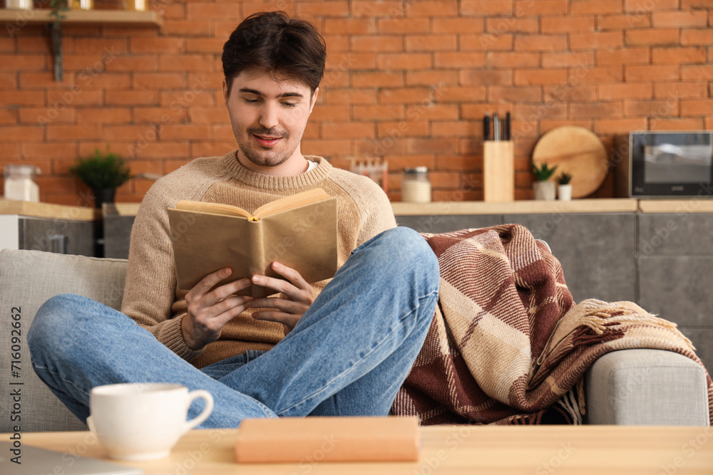 Young man reading book on sofa at home Young man reading book on sofa at home