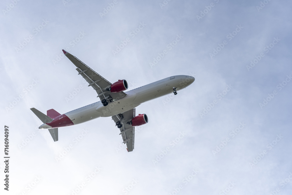 fuselage of a passenger plane at low altitude near the runway with the landing gear deployed