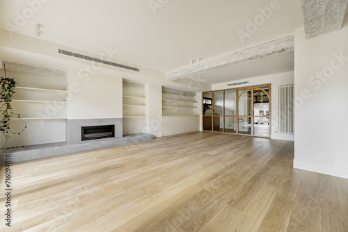 A large empty living room with a wall with a fireplace and plaster shelves
