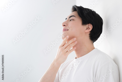 頬を触るアジア系（日本人）男性 爽やかな脱毛やスキンケアのイメージ クローズアップ メンズの美容やビューティーに photo