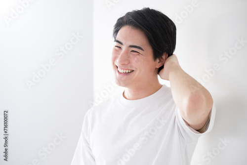 髪を触るアジア系（日本人）男性 爽やかな脱毛やスキンケアのイメージ　照れる photo