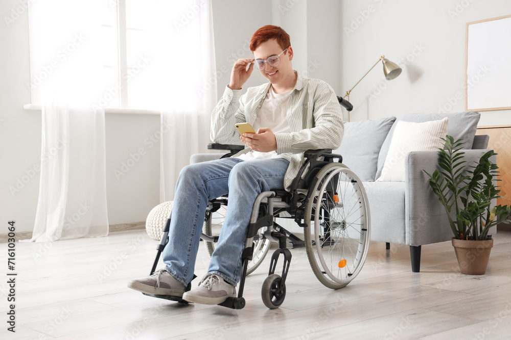 Young man in wheelchair using mobile phone at home Young man in wheelchair using mobile phone at home