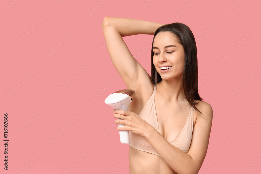 Beautiful young woman with modern photoepilator on pink background Beautiful young woman with modern photoepilator on pink background