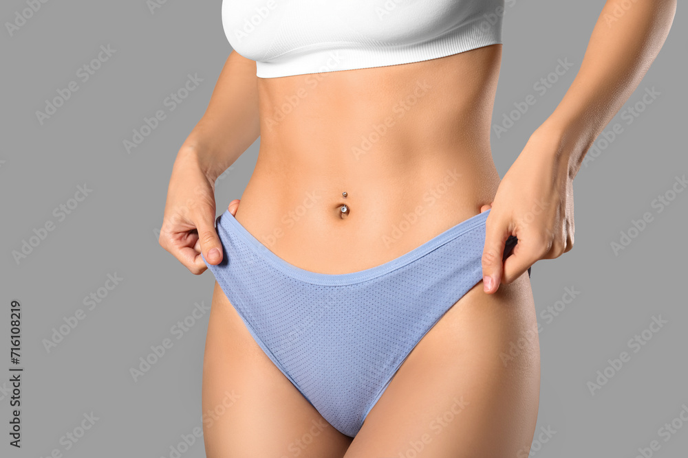 Young woman in panties on grey background - obrazy, fototapety, plakaty 