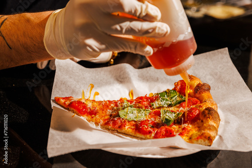 Drizzling hot honey on a pizza slice