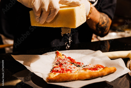 Shaving fresh cheese on a pizza slice