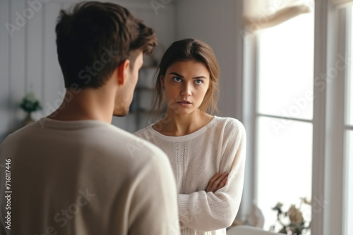 Оffended young woman and man argument, сlose up husband in front and upset wife looks away behind quarrel at home. Family conflict, crisis, psychological abuse, relationships concept