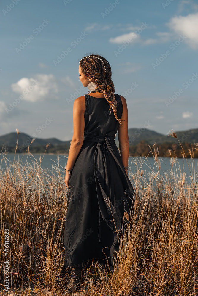 Obraz premium beautiful young stylish woman on the field at sunset