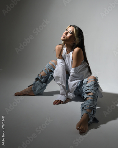 Full length portrait of brunette female asian model wearing casual clothes, double denim jean pants. Isolated on dark studio background with shadows