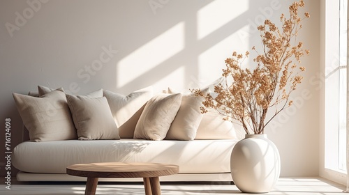 A Minimalist interior design of a modern living room, sofa and stump pillows, in a room with morning sunlight streaming through the window. © Phoophinyo