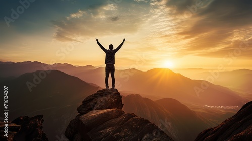 Happy man raising his arms jumping to the top of the mountain, successful businessman celebrating success on the cliff, business success concept silhouette backlit.