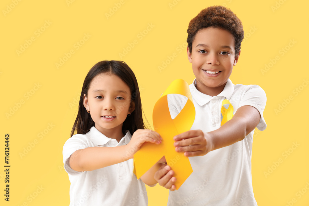 Cute little children with yellow ribbons on color background. Childhood cancer awareness concept Cute little children with yellow ribbons on color background. Childhood cancer awareness concept