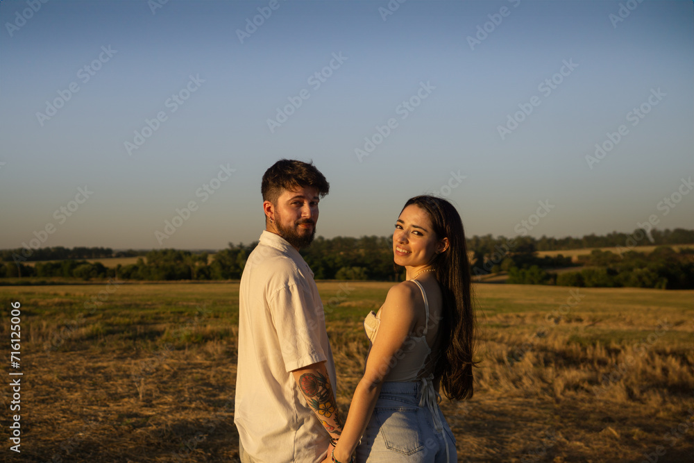 Beautiful couple hugging and kissing in a field at sunset Beautiful couple hugging and kissing in a field at sunset