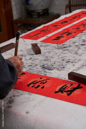 An old calligrapher writes couplets during the Chinese Year of the Dragon. Translation: The auspicious energy brings auspiciousness and the wealth is abundant.