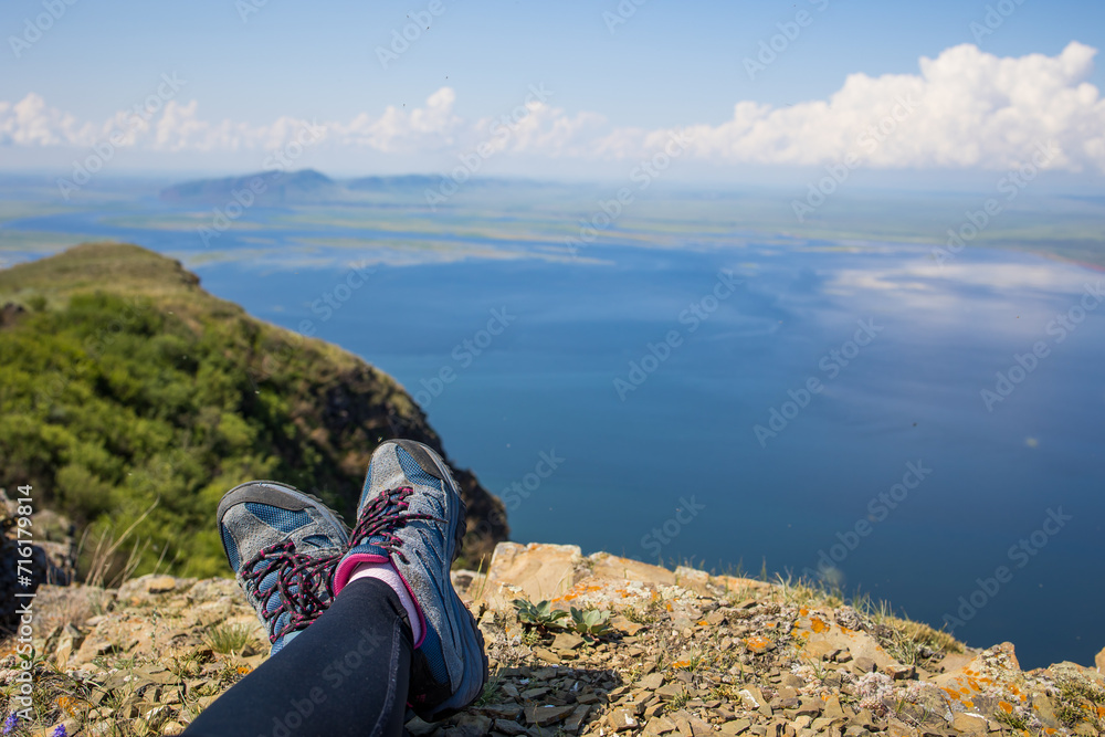 Fototapeta premium tourist legs in trekking shoes, sea view from a cliff